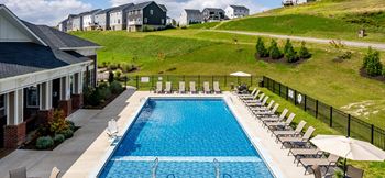 a swimming pool in front of a house with a hill behind it at The Flats at Summit Station, South Park, Pennsylvania